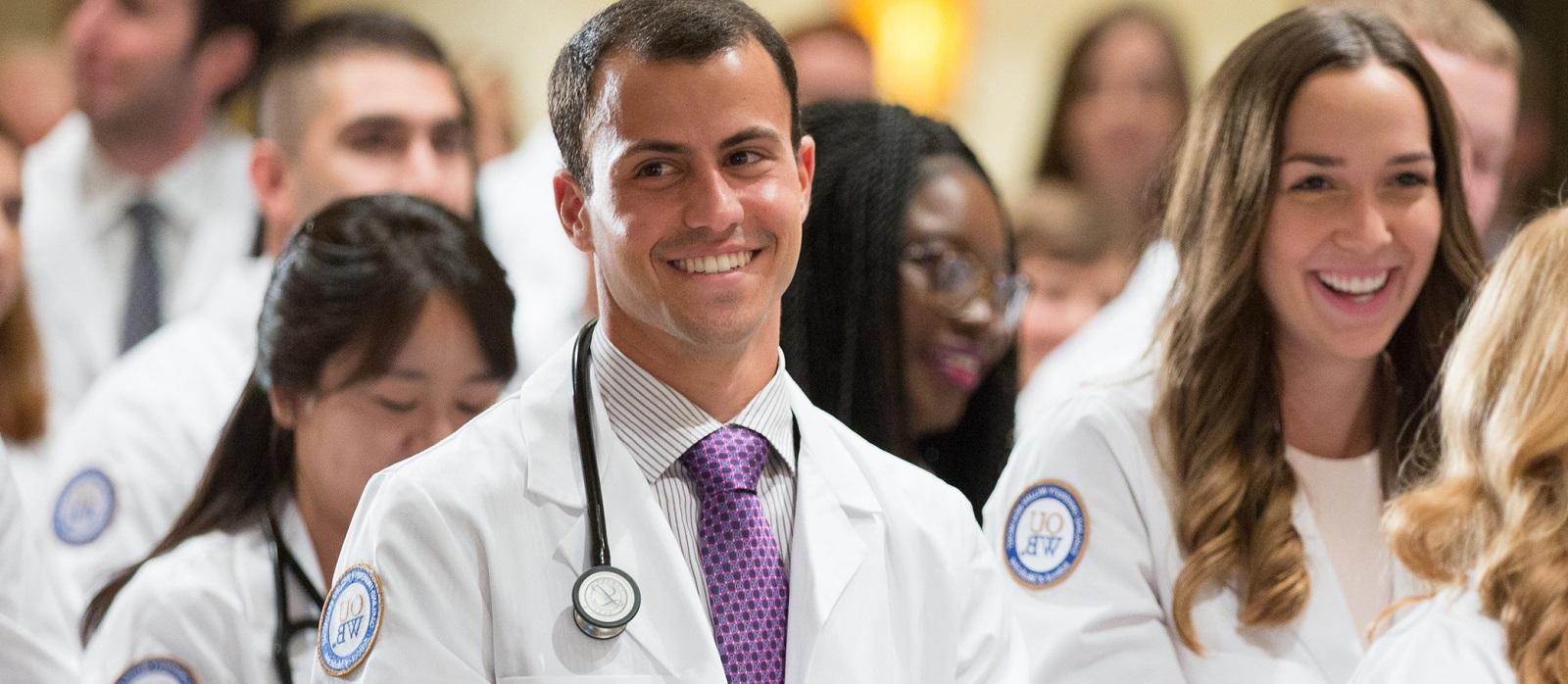 A student smiles as he stands in the crowd at the White Coat ceremony.
