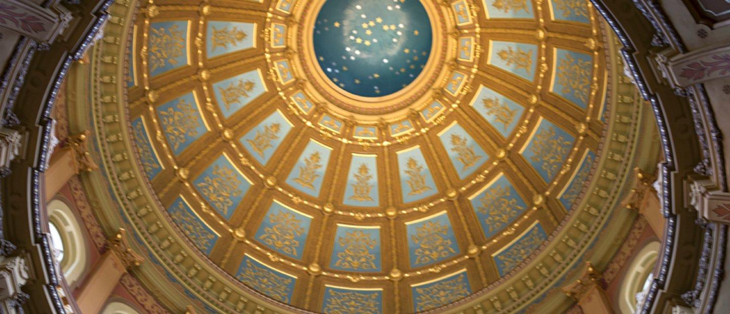 A photo looking up at an ornate blue and gold dome ceiling.